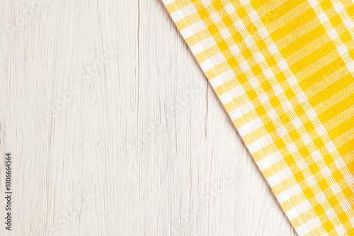 White washed wood texture background with a vibrant yellow gingham tablecloth corner