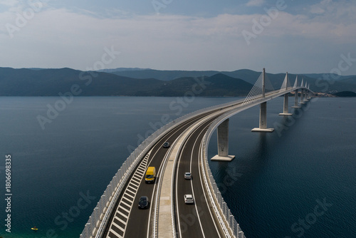 Aerial view of the Peljesac Bridge gracefully stretches across the shimmering Adriatic Sea, connecting the Croatian mainland to the Peljesac Peninsula, Komarna, Dubrovnik-Neretva County, Croatia.
