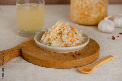 Homemade sauerkraut salad with carrots, pepper and garlic and sauerkraut juice or brine on a table.