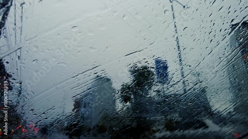Heavy Raindrops Falling on Car Windshield While Driving in City Traffic