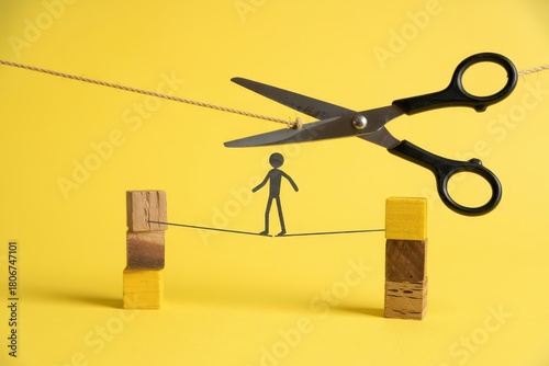 Large metal scissors threaten to sever a thin rope upon which a tiny cutout figure balances precariously