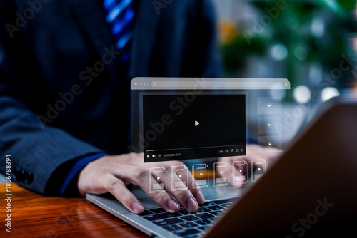 Hands typing on a laptop with a floating video player interface, illustrating digital media streaming, online video platform technology, modern multimedia content management in a business environment.
