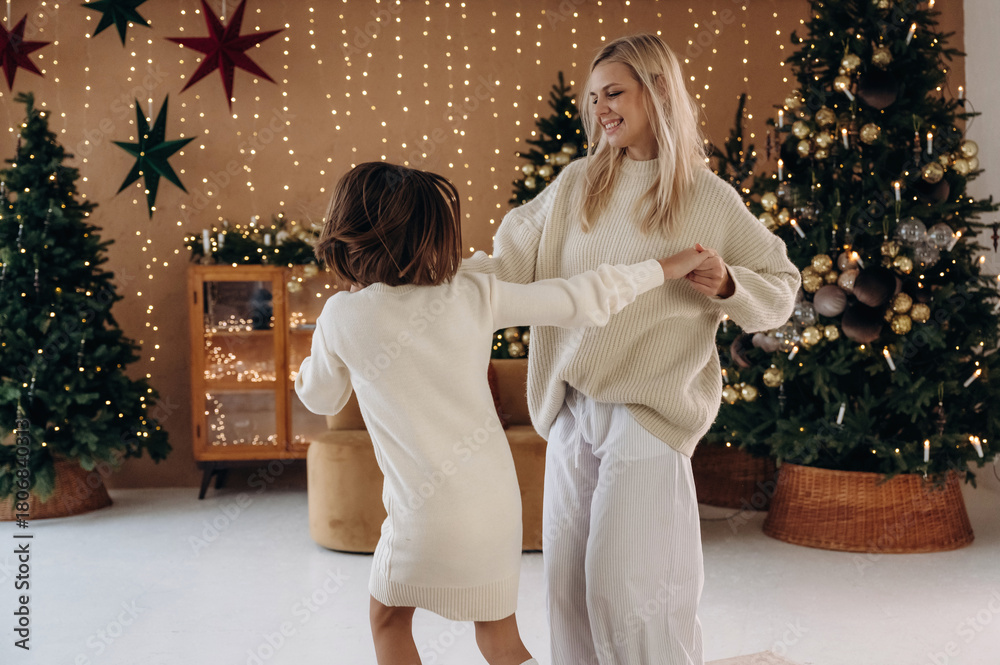 Naklejka premium Holding the hands. Mother and daughter are celebrating New Year at home in domestic room