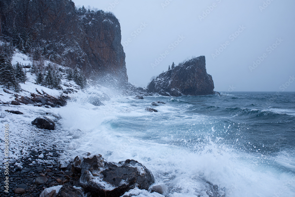 Obraz premium Rocky coastline during winter storm, icy waves crashing, snow-covered cliffs, cold dramatic atmosphere, realistic texture details