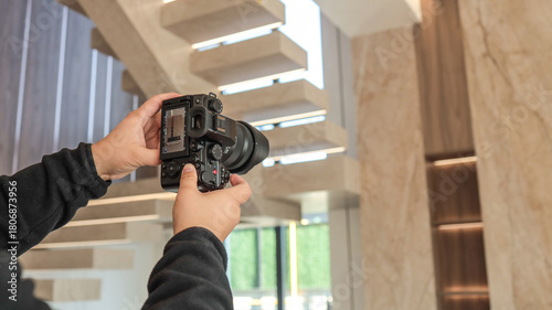 Photographer holding a camera, capturing a modern interior with a staircase