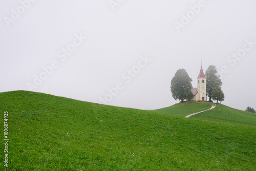 Église de Saint-Thomas dans la brume – colline verdoyante en Slovénie