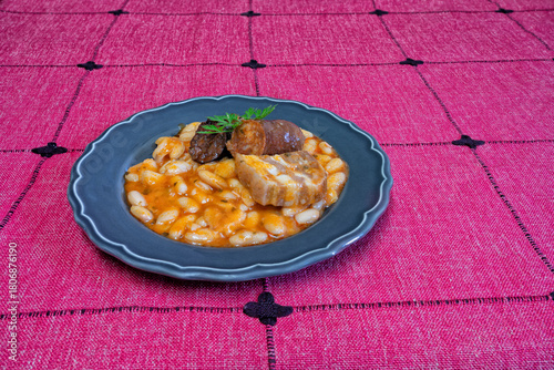 A plate of beans on a red tablecloth