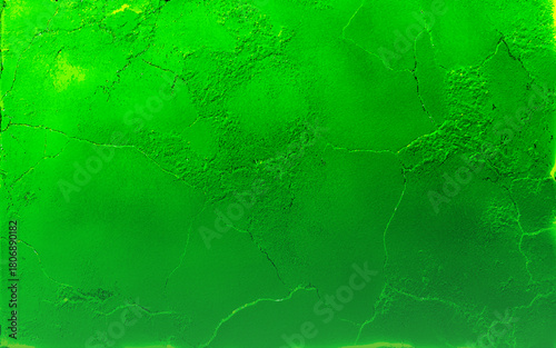 An aging green wall shows signs of wear with cracking and peeling paint, revealing the concrete beneath. The texture highlights the wall's deterioration and time's effect on the surface. Green paint