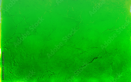 An aging green wall shows signs of wear with cracking and peeling paint, revealing the concrete beneath. The texture highlights the wall's deterioration and time's effect on the surface.