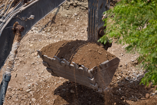 Wallpaper Mural Excavator bucket digging into soil during construction work, showing power, precision, and heavy machinery in action. Torontodigital.ca