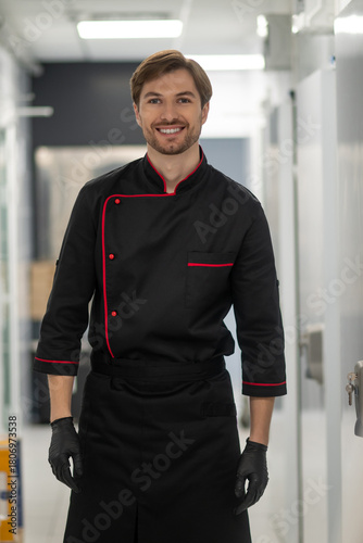 Chef in uniform moving through modern kitchen interior