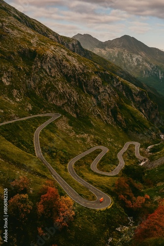 Winding mountain road in autumn with a small car