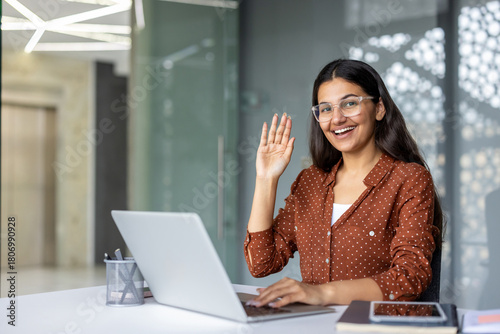 Принти на полотні Indian woman in a bright home office smiling and waving during a laptop video ca