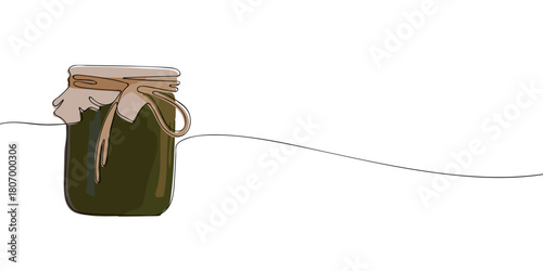 A rustic glass jar filled with a dark substance, covered with a cloth lid tied with a string, giving it a homemade, artisanal appearance