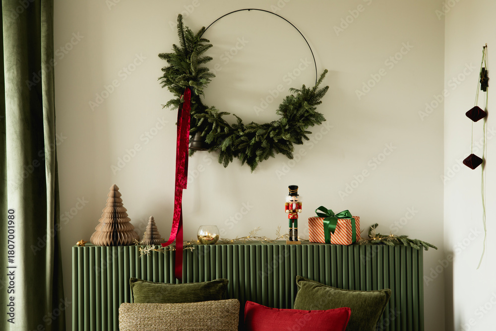 Obraz premium Minimal Christmas styling with a large wreath, decorative trees, and a nutcracker figurine set on a green console.