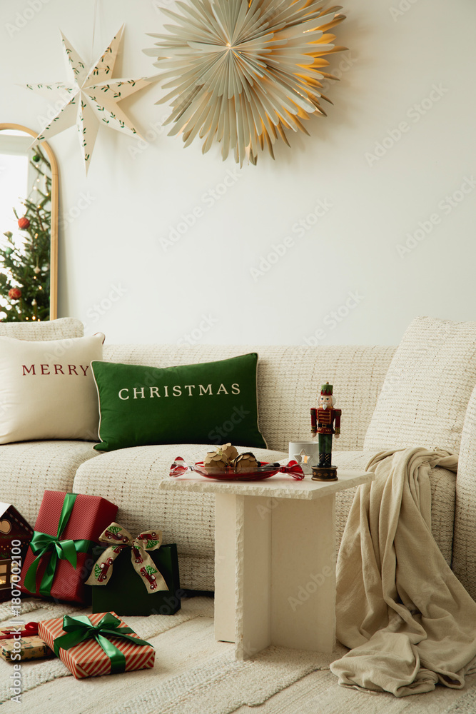 Obraz premium Warm holiday living room with Christmas cushions, wrapped gifts, and soft neutral textures creating a festive and inviting atmosphere.