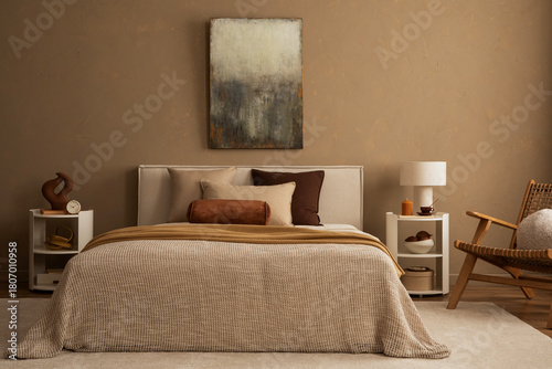 Warm-toned bedroom with textured bedding, decorative pillows and a modern nightstand.