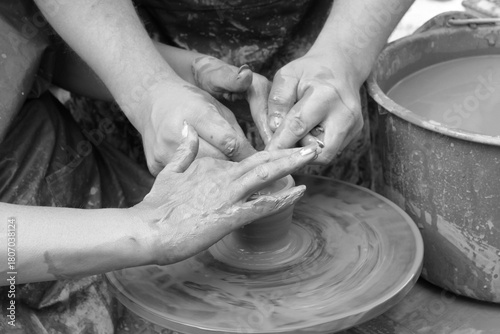 Retro style black and white photo depicting process of learning to make pottery with close-up of person's hands holding soft clay
