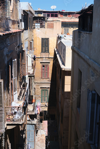 Narrow well-like courtyard of old residential building with aged facades, balconies, and weathered windows. Historical centre of Alexandria, Egypt