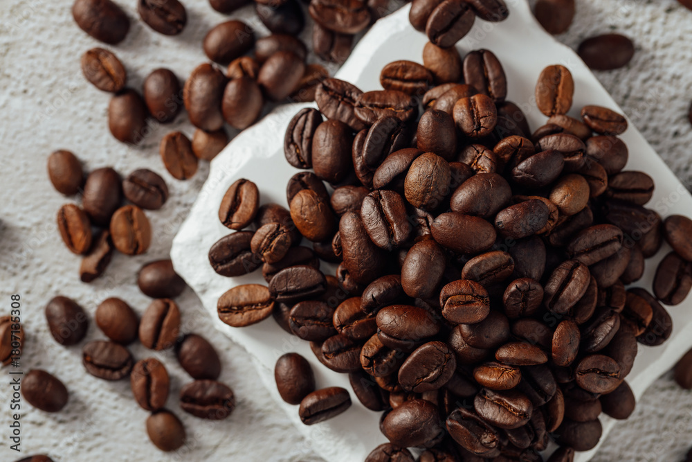 Obraz premium Freshly Roasted Coffee Beans on White Surface with Texture Background