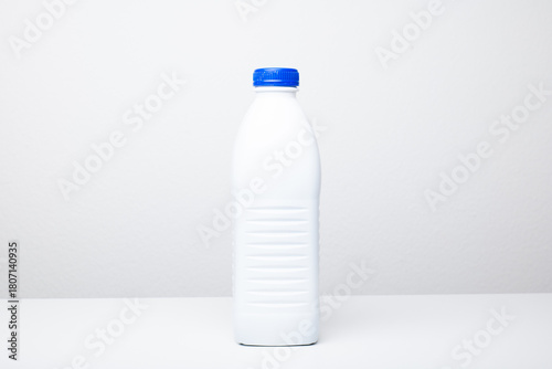 A clean, vertical shot of a blank, generic opaque white plastic bottle with a blue screw-top cap. Studio shot, isolated on white, no people