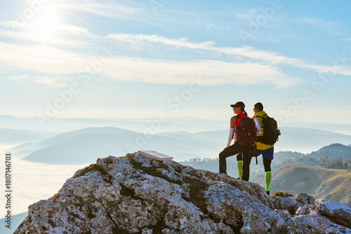 Couple enjoying breathtaking view from mountain peak during sunset on a clear day
