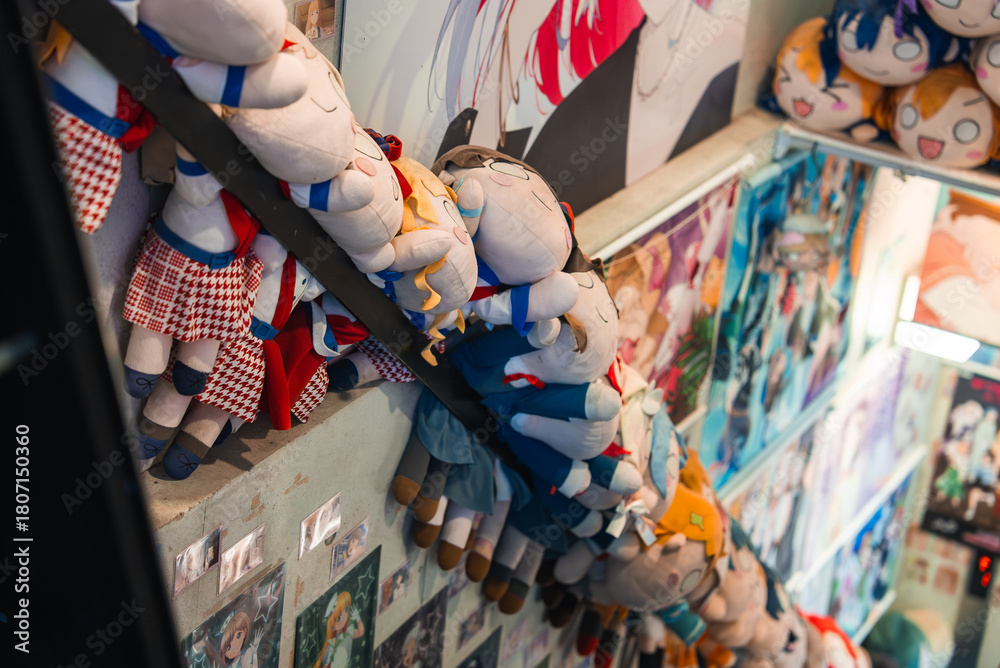 Fototapeta premium A narrow Tokyo anime shop staircase is lined with plush doll characters and walls of manga and idol posters, creating a playful tunnel of collectibles in Akihabara.