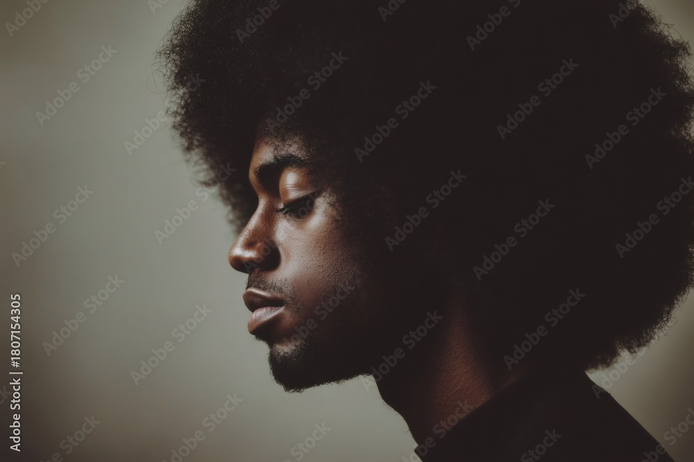 Obraz premium Young Black man with natural afro hair in profile, eyes closed, reflecting peacefully in a studio setting