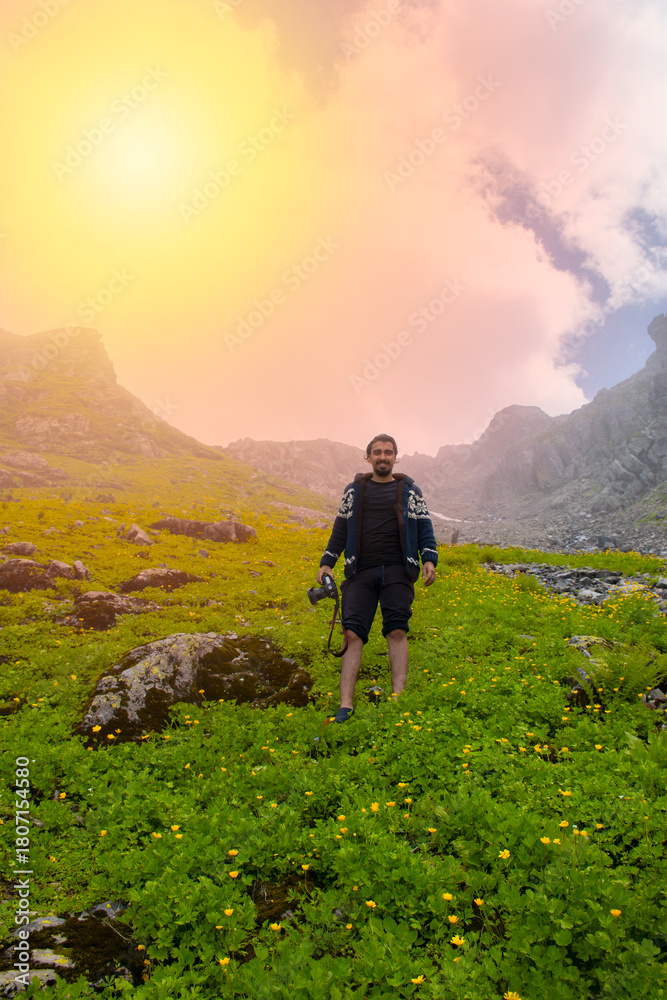 Obraz premium Young photographer poses in a mountainous grassy area..