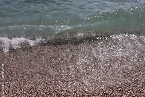 Foto Crystal clear waves crashing on a pebbled beach