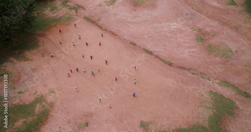 Aerial view of people playing on a field with lush green trees bordering the red-brown earth, Kumi, Eastern Region, Uganda.
