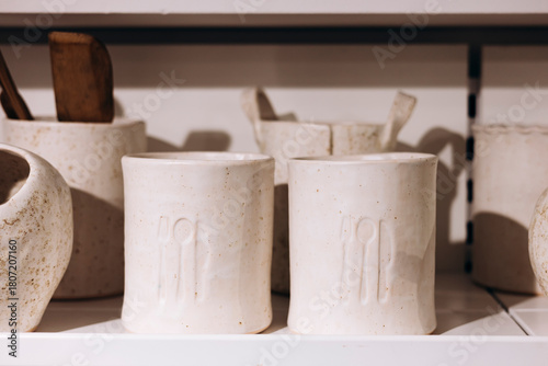 Close-up of handmade ceramic kitchen containers on a white shelf.
