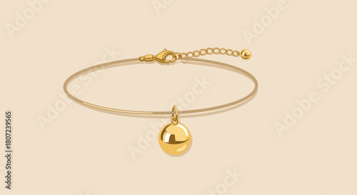 A delicate gold bracelet featuring a thin chain. A gold sphere dangles gracefully from the center, against a light backdrop