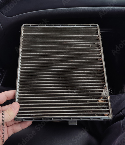 Dirty cabin air filter being replaced in a car.