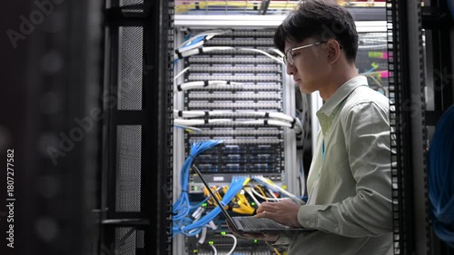 Computer engineer is setting up network in server room,Systems Maintenance Technician,Male engineer working in server room at modern data center