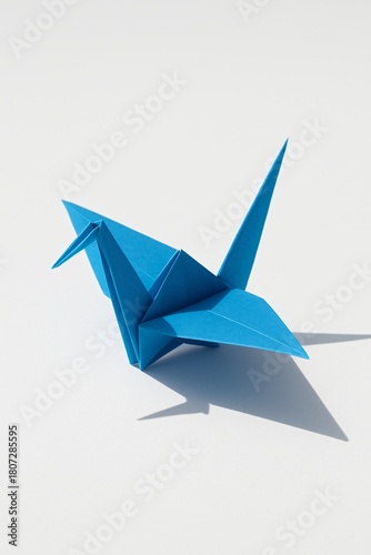 Blue origami crane bird casting shadow on white