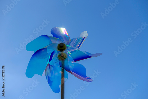 Colorful wind spinner shines in bright sky during sunny day, creating a playful atmosphere in the outdoor park