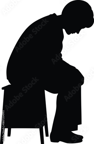 Silhouette of a man sitting sadly on a stool, head down