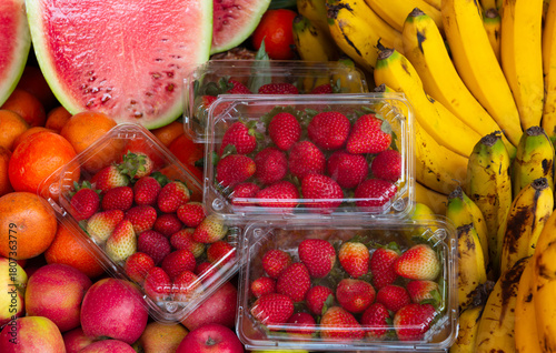 Freshly Packaged Red Strawberries with Assorted Fruits in Background

Fresh, ripe red strawberries packaged in a container with apples, bananas, and watermelon in the background at a vibrant market 