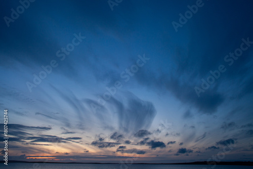 Tableau sur toile Dark cirrus clouds in a dark blue sky over the first light of sunrise over the N
