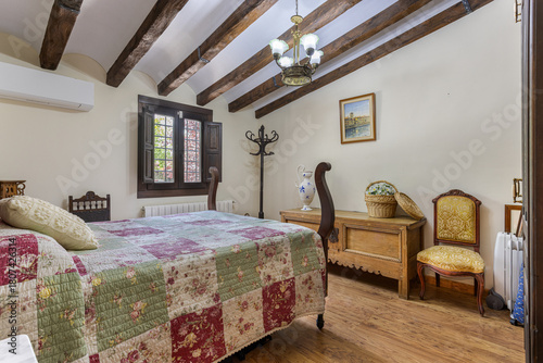 Elegant rustic bedroom with wooden beams, vintage furniture, and floral patchwork bedding