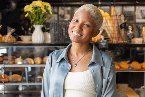 Obraz na płótnie African American woman with short blond hair smiles and holds laptop in her hands