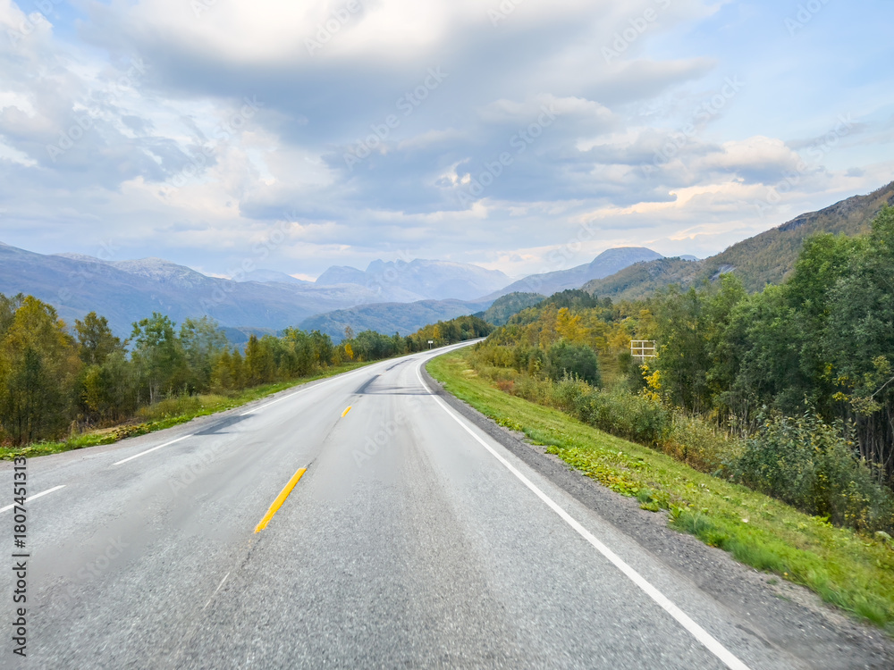 Naklejka premium Tranquil drive through norway's vibrant autumn scenery on a picturesque route with breathtaking natural beauty