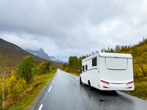 A motorhome parked by the road in the autumn landscape of Senja Island, Northern Norway, with fjords and mountains.