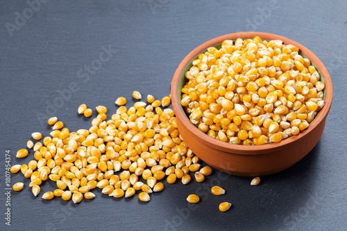 Bowl with popcorn kernels on a gray stone surface