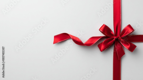 Clean white background with a single red Christmas ribbon and bow arranged on the side, minimal elegant holiday design, lots of negative space.