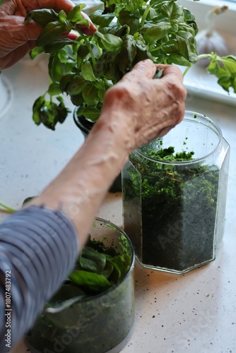 The process of preparing pasta with pesto from spinach, basil, green peas and green parsley: mixing the leaves