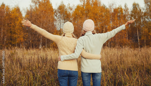 Happy young women friends having fun in autumn park, girlfriends walking together outdoors