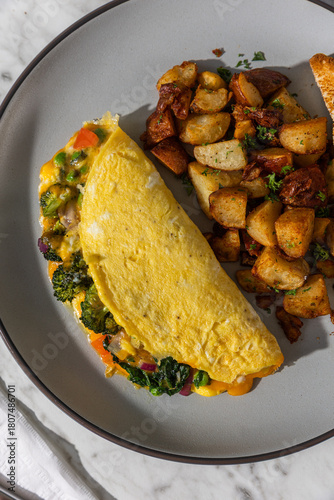omelette with toast and hashbrowns on plate in hard light