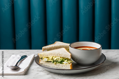 egg salad sandwich with tomato soup on marble table
